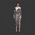 Woman In Colorful Printed Top And Pants Standing Stylishly Against Gray Background