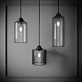 Three Modern Glass Pendant Lights with Cylindrical Shades Hanging Illuminated in Neutral Background