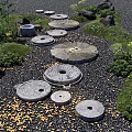 Japanese Zen Garden With Stone Millstones Pebble Pathway Lantern And Green Plants