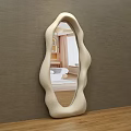Modern Irregular Shaped Mirror With Cream Frame Reflecting Living Room Interior On Wooden Tabletop