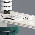 Cream Colored Desk With Open Book White Coffee Cup Stacked Decorative Objects And Green Chair