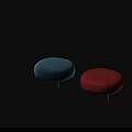 Two Round Upholstered Footstools in Blue and Red with Metal Legs on Black Background