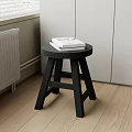 Black Round Side Table with Three Legs and Books on Wooden Floor Near White Cabinets