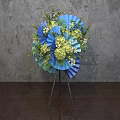 Blue Green Floral Arrangement With Fan Shaped Decor On Tripod Stand Grey Wall Wooden Floor