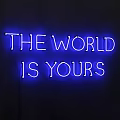 Yellow Neon Decorative Light with THE WORLD IS YOURS Text on Dark Background