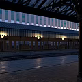 Well Lit Railway Station Platform Featuring Glass Canopy Tracks And Lamps