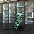 Detailed Green Grape Sculpture in Transparent Display Case on Black Tabletop