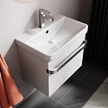Wall Mounted White Washbasin with Round Backlit Mirror Orange Towels Side Table Toiletries and Plant