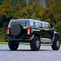 Black Hummer SUV Parked On Outdoor Road With Green Trees Background