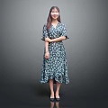Woman in Blue Green Floral Dress with Ruffled Hem Standing Against Gray Background