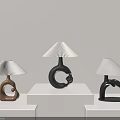 Three Modern Artistic Table Lamps With Unique Bases On White Display Stands 3d model