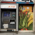 Outdoor Commercial ATM Machine Installed On Brick Wall With Vegetable Poster
