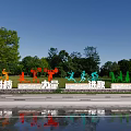 Colorful Human Shaped Sculptures Displayed On Grassland With Trees Sky And Water Pool Reflection