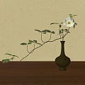 Black Ceramic Vase With White Flower And Green Leaves On Wooden Tabletop Against Beige Wall