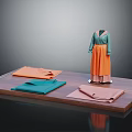 Clothing Mannequin in Green Top and Orange Skirt with Folded Fabrics on Display Platform