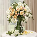 Transparent Glass Vase with Hydrangea White and Cream Flowers Green Leaves and Petals Scattered Around