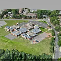 Aerial View of Building Complex with Green Spaces Trees Parking Areas Roads and Children's Playground