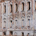 Dilapidated Building Exterior Wall With Broken Windows Peeling Paint Exposed Red Bricks And Decorative Arches