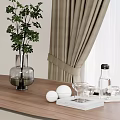 Green Plant in Glass Vase on Wooden Table with Curtain Indoor and White Balls Glassware