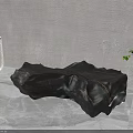 Black Irregular Shaped Sculpture Artistic Carving With Green Plants And Gray Background