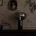 Glass Table Lamp with Black Base and Vintage Radio on Floral Wallpaper Background
