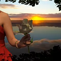 Beautiful White Flower Held In Red Dress Against Sunset Sky Water Surface With Green Leaves