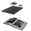 Silver Apple Laptop on Desk with Stacked Books Open Magazine and Coaster