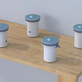 Four Compact White Household Appliances With Blue Lids On Wooden Table