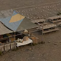 Outdoor Gathering Area With Tent Canopies Picnic Tables Storage Boxes And String Lights On Sand