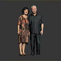 Elderly Man In Dark Green Shirt Standing With Woman In Floral Dress Against Gray Background