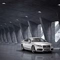 Sleek White Audi Sedan Parked In Modern Concrete Architectural Space With Ambient Lighting