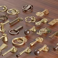 Various Vintage and Modern Brass Handles with Decorative Designs on Wooden Surface