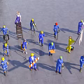 Group of Workers in Blue Worksuits and Yellow Hard Hats Performing Tasks on Concrete Ground