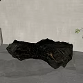 Black Stone Sculpture Carving Featuring Irregular Shape Textured Surface White Potted Plant Gray Wall Floor