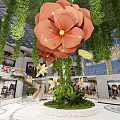 Mall Atrium Interior With Large Orange Flower Green Hanging Vines And Circular Plant Base