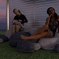 Relaxing Garden Landscape With Two Women On Gray Bean Bag Sofas And Sunset Sky