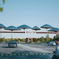 Modern Entrance Gate With Umbrella Shaped Canopies Logo Sign And Vehicles In Parking Area
