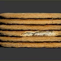 Stack of Golden Crackers with Small Holes on Surface on Dark Background