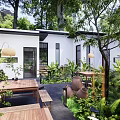 Outdoor Restaurant Patio With Wooden Tables Benches Greenery Trees Clay Pots White Building Lantern Lights