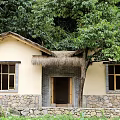 Traditional Rustic Country Cottage With Thatched Roof Stone Wall And Green Trees