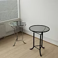 Two Modern Side Tables With Glass Tops And Silver Black Metal Frames In Room Corner