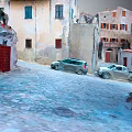 Ancient Small Town Scenery With Cobblestone Street Old Buildings Red Doors And Windows Parked Cars