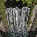 Natural Scenery Featuring Waterfall Rocky Outcrops With Lush Green Vines And Trees