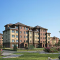 Multistory Residential Building With Red Brick Beige Exterior Green Lawn Flowers And Trees