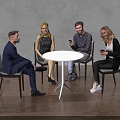Group of Four People Sitting Around White Round Table in Modern Room with Gray Wall