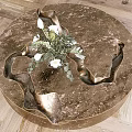 Round Metallic Coffee Table With Sculptural Indents And White Flower Arrangement On Wooden Floor