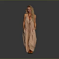 Blonde woman in light brown halter maxi dress with hands in pockets against gray background