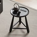 Minimalist Black Round Side Table with Teapot Tray Near Wicker Chair on Herringbone Floor