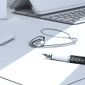 Elegant Fountain Pen Resting on Lined Notebook Paper with Necklace Seal and Laptop in Background