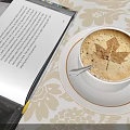 Coffee Cup With Maple Leaf Latte Art Next To Open Book On Floral Tablecloth